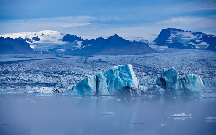 Icebergs floating in glacial lagoon with mountains in background