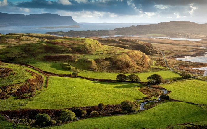 Rolling green hills and a bay under a cloudy sky