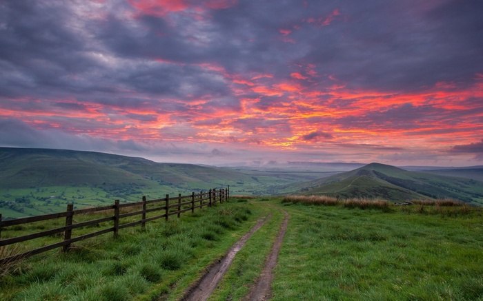 Dramatic sunset over rolling hills with a wooden fence