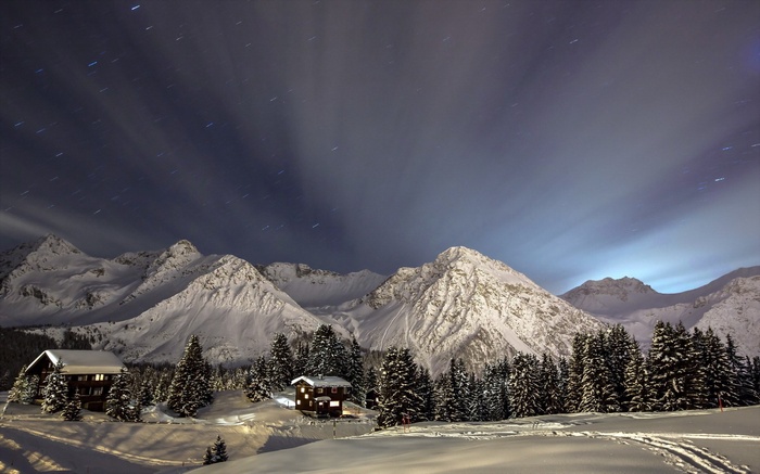 Snowy mountains at night with cabins and stars