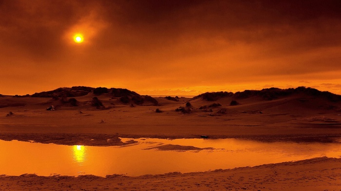 Desert landscape with sun and water reflection