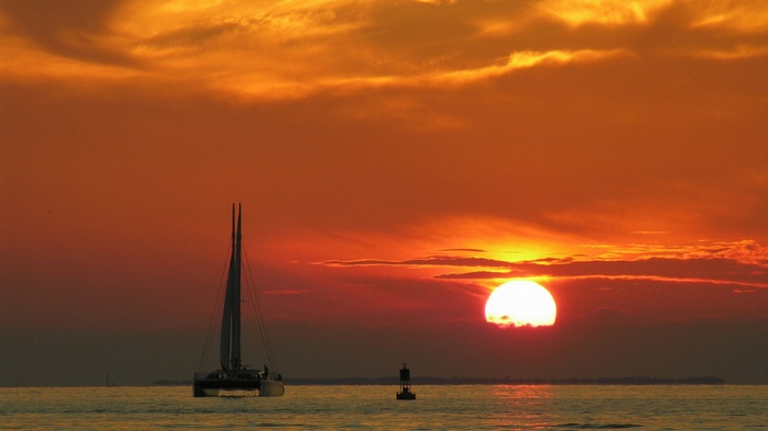 Sailboat and buoy at sunset over the ocean