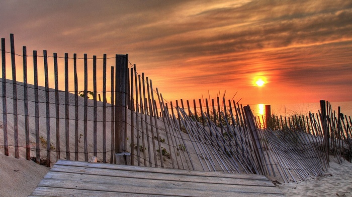 Beach fence and boardwalk at sunset