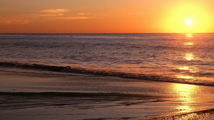 Sunset over the ocean with waves on the beach