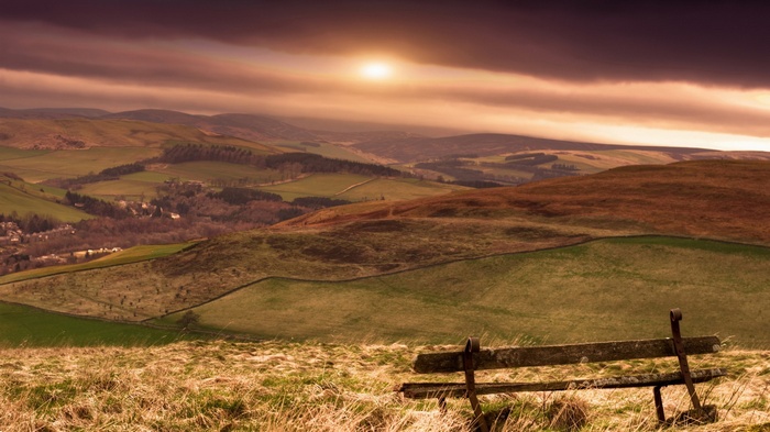 Wooden bench overlooking rolling hills at sunset