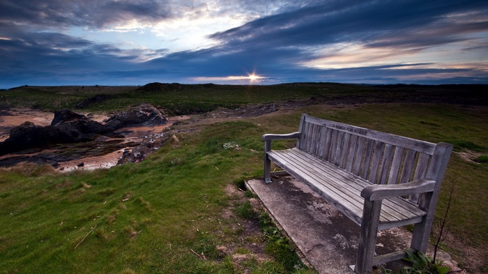 Wooden bench overlooking a coastal landscape at sunset