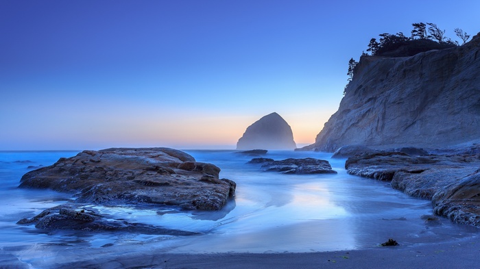 Ocean waves crash on rocky shore at dusk