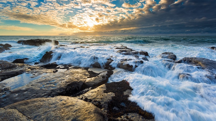 Waves crashing on rocky shore at sunset