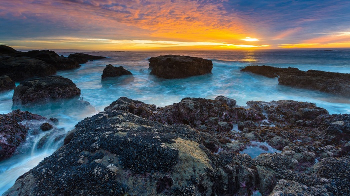 Ocean waves crashing on rocky shore at sunset