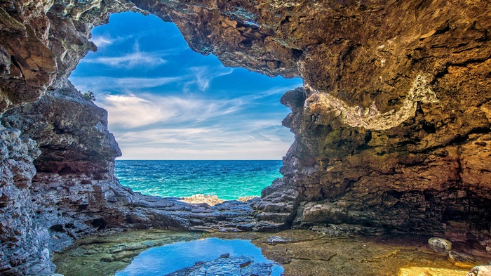 Cave opening overlooking a turquoise ocean and blue sky