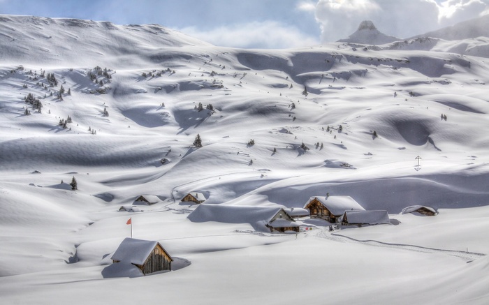 Snowy mountain landscape with cabins and a flag
