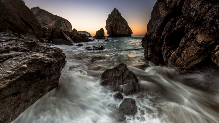 Rocky coastline with waves at sunset