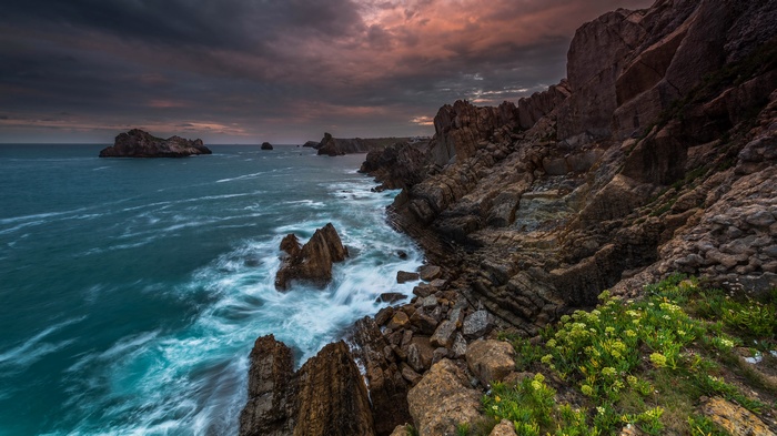 Rocky coastline with ocean waves and dramatic sky