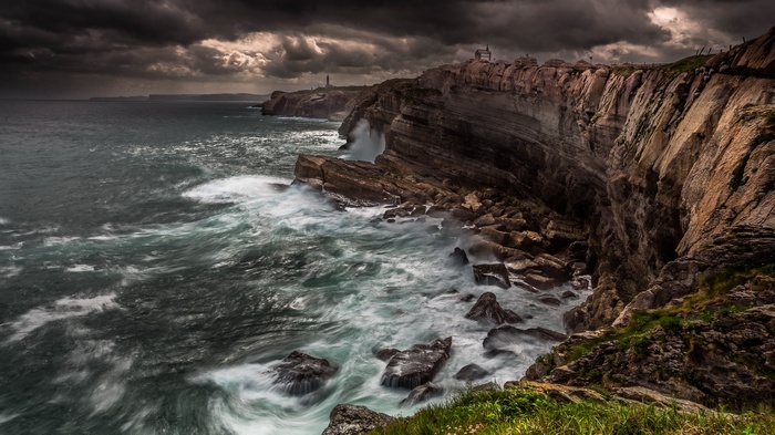 Stormy sea crashing against rocky cliffs with lighthouses