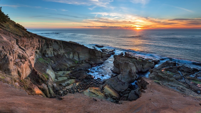 Sunset over rocky coastline with ocean waves