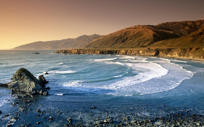 Coastal cliffs and ocean waves at sunset