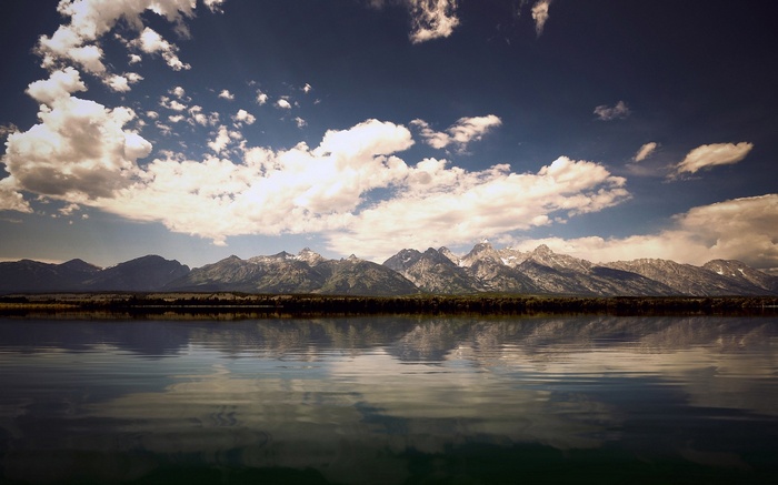 Mountains reflected in a lake under a cloudy sky