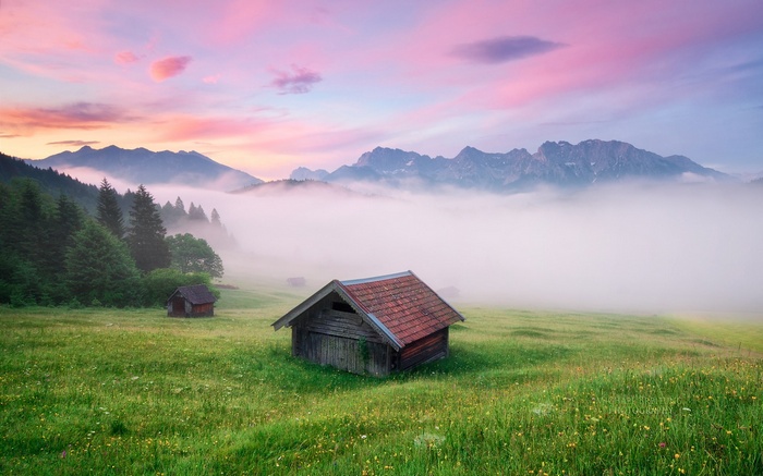 Wooden huts in a misty mountain valley at sunrise