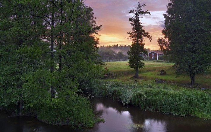 Red house by a river at sunset