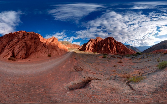 Red rock mountains and a dirt road under a blue sky