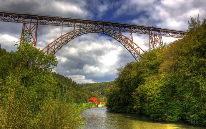 Bridge over a river with trees and a house