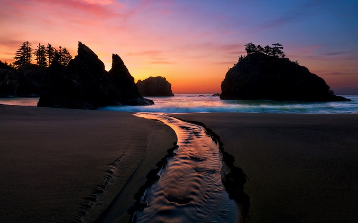 Sunset over a beach with a stream and rock formations