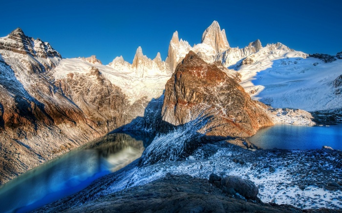 Snow-capped mountains and a blue lake under a clear sky