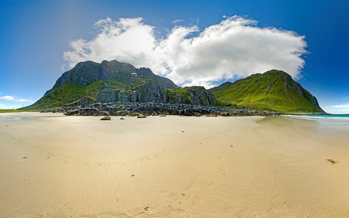 Sandy beach with green mountains and blue sky