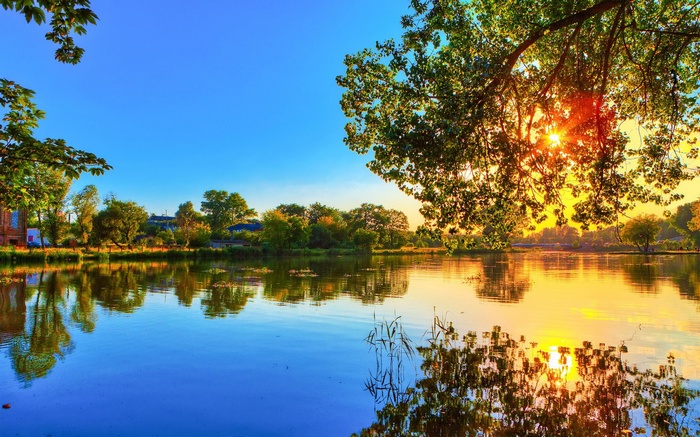 Sunset over a calm lake with trees and reflections