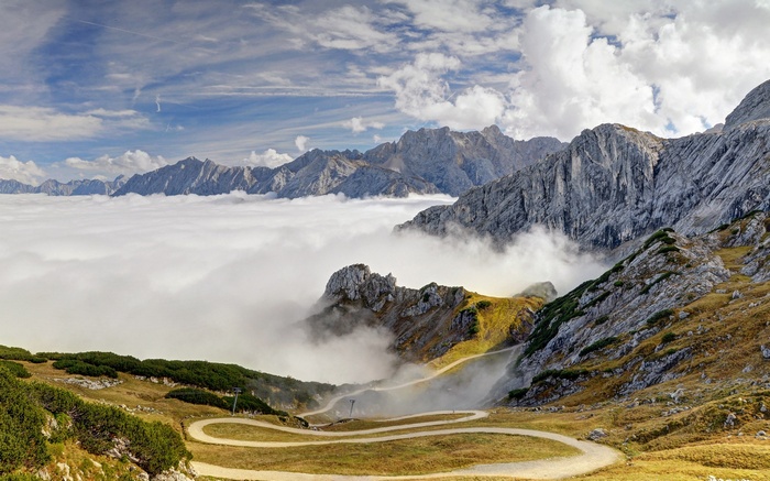 Mountain range above clouds with winding road