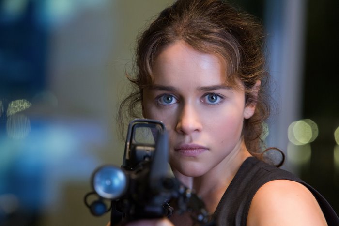 Emilia Clarke aiming a rifle