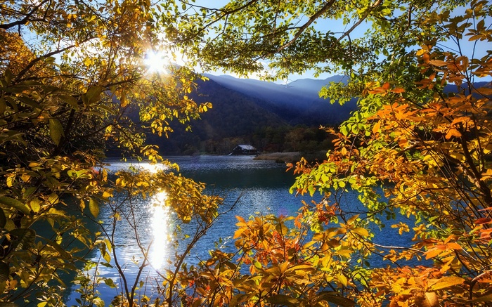 Autumn lake with sunbeams through trees and mountains