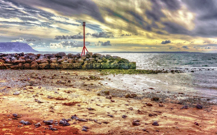 Coastal marker on a rocky breakwater with a beach