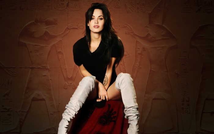 Megan Fox sitting in front of Egyptian hieroglyphs