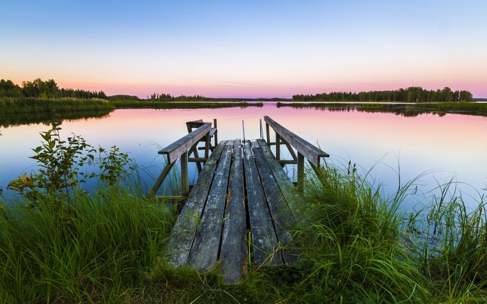 Wooden dock on a calm lake at sunset