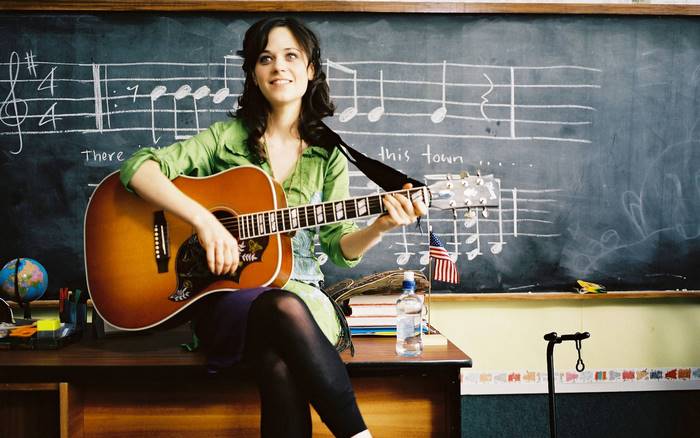 Zooey Deschanel playing guitar in a classroom