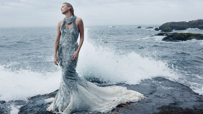 Charlize Theron on a rocky shore with waves
