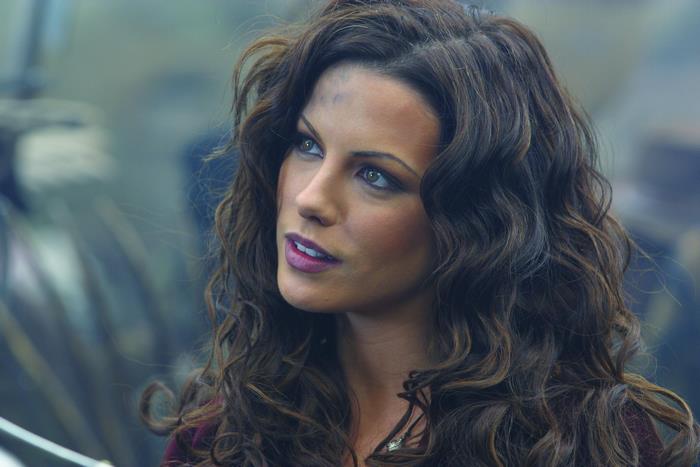 Kate Beckinsale with long curly hair in thoughtful pose