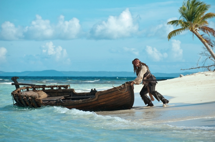 Johnny Depp pushing a boat on a beach