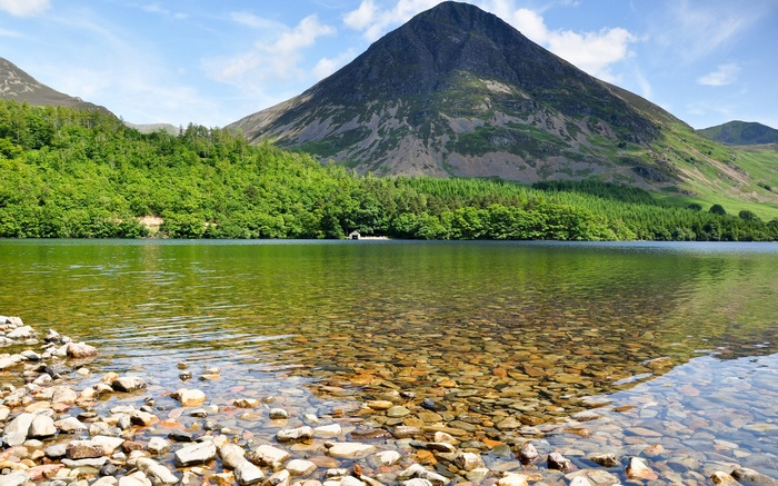 Mountain lake with rocky shore and green forest