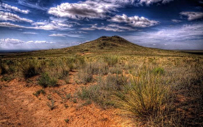 Desert landscape with a large hill and cloudy sky