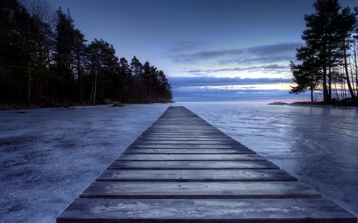 Wooden pier on a frozen lake at dusk
