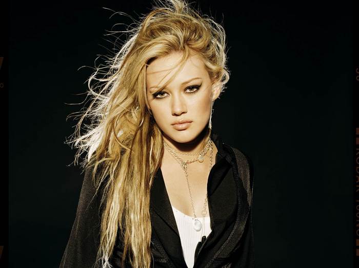 Hilary Duff posing against a black background