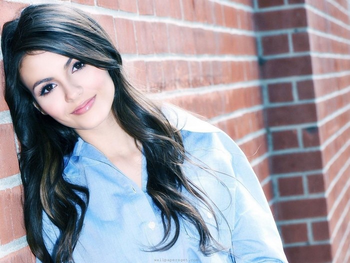 Victoria Justice leaning against a brick wall