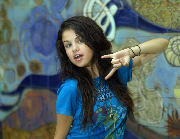 Selena Gomez posing in front of a mural