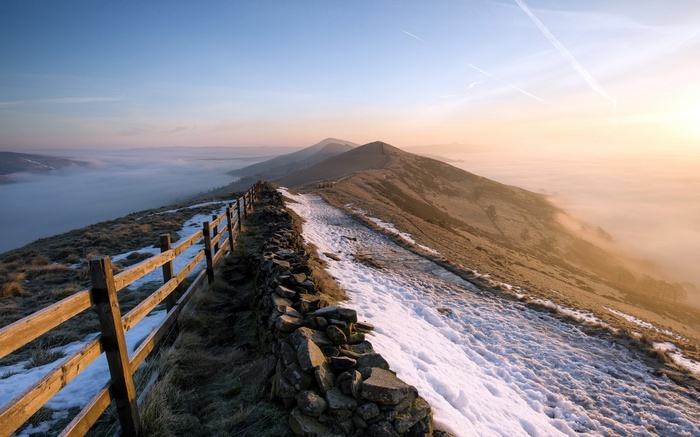 Mountain ridge with fence and fog at sunrise