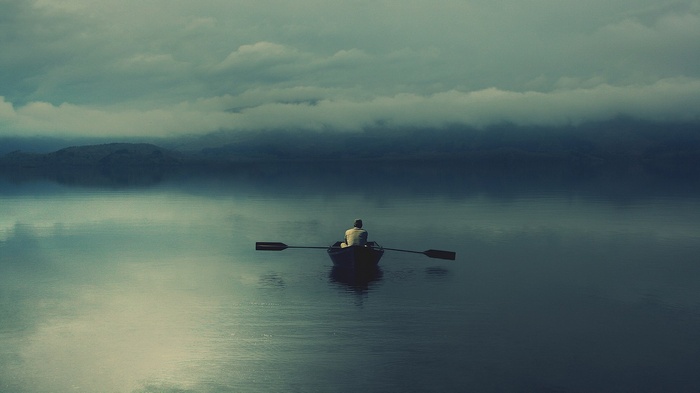 Man rowing a boat on a misty lake