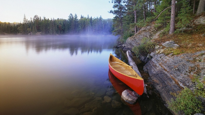 Red canoe on a misty lake at sunrise