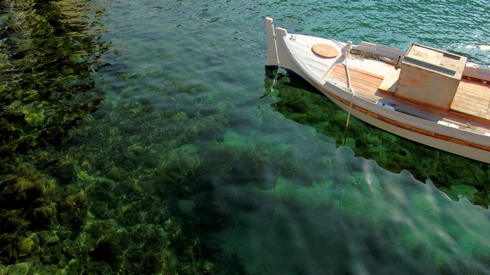 White boat floating on clear green water with visible seabed
