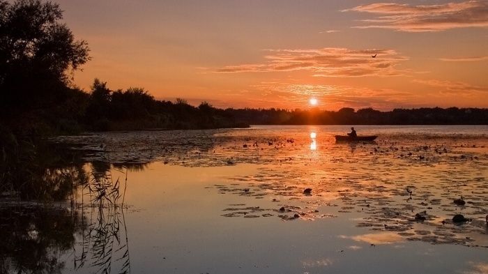 Person in a boat on a lake at sunset